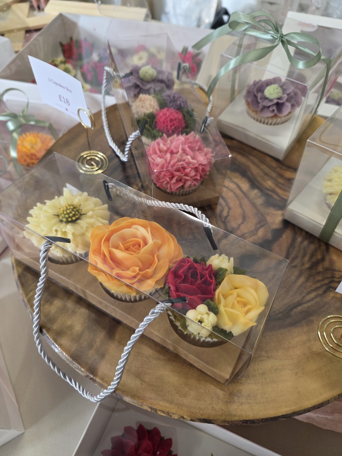 Three floral cupcakes in a clear gift carrier